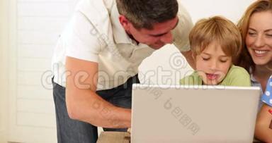活泼开朗的父母和孩子一起用手提电脑做工艺品
